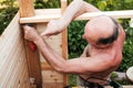 Mature man using tools building structure outside