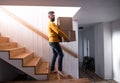 Mature man walking down stairs in house, holding moving boxes. Royalty Free Stock Photo