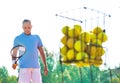 Mature man walking while holding tennis racket against balls on court Royalty Free Stock Photo