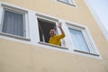 Mature man waving hand greeting his friend from window. Royalty Free Stock Photo