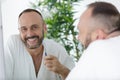 Mature man wearing bathrobe and holding toothbrush