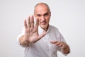 Mature man in yellow shirt showing sign stop with hand. Royalty Free Stock Photo