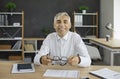 Portrait of happy senior businessman sitting at office table and smiling at camera Royalty Free Stock Photo