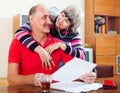 Mature man with wife reading financial documents