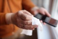 Mature man wipes with a disinfecting cloth heis smartphone after returning home. Safety during COVID-19 outbreak in public places