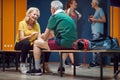 Mature man and woman facing each other while sitting in gym locker room and talking before training Royalty Free Stock Photo