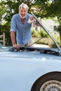 Portrait Of Mature Man Working On Engine Under Hood Of  Restored Classic Sports Car Outdoors Royalty Free Stock Photo