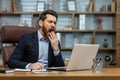 Mature man yawning inside classic office, senior businessman in workplace sleepless and overworked, boss in business Royalty Free Stock Photo