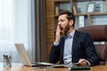 Mature man yawning inside classic office, senior businessman in workplace sleepless and overworked, boss in business Royalty Free Stock Photo