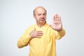 Mature man in yelloe tshirt showing sign stop with hand. Royalty Free Stock Photo