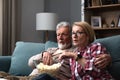 Mature married couple entertaining observing terrified TV program. Senior husband and wife watching horror movie or film at home