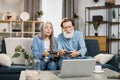 Mature married couple with joysticks in hands playing video games while sitting on comfy couch Royalty Free Stock Photo