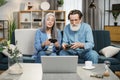 Mature married couple with joysticks in hands playing video games while sitting on comfy couch Royalty Free Stock Photo