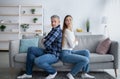 Mature married man and his wife sitting back to back on sofa, not knowing how to make peace after conflict