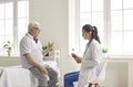 Elderly man talks about his health condition to his female doctor who is taking notes on clipboard. Royalty Free Stock Photo