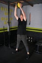 Mature man, weighted ball smashes exercise, indoor garage home gym Royalty Free Stock Photo