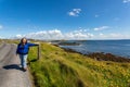 Mature Mexican woman in blue jacket on the coastal road with dramatic shoreline scenery Royalty Free Stock Photo