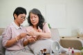 A mature middle-aged Asian woman applies makeup to her friend in the living room Royalty Free Stock Photo