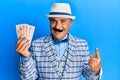 Mature middle east man with mustache wearing elegant vintage style holding pounds banknotes smiling happy pointing with hand and