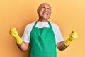 Mature middle east man wearing cleaner apron and gloves very happy and excited doing winner gesture with arms raised, smiling and