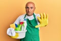 Mature middle east man wearing cleaner apron holding cleaning products with open hand doing stop sign with serious and confident Royalty Free Stock Photo