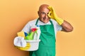 Mature middle east man wearing cleaner apron holding cleaning products smiling happy doing ok sign with hand on eye looking Royalty Free Stock Photo
