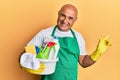 Mature middle east man wearing cleaner apron holding cleaning products smiling happy pointing with hand and finger to the side Royalty Free Stock Photo