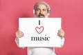 Mature modern man with headphones holding a sign with i love music text