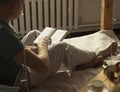 Mature modern man sitting on bed and reading book, side or back view