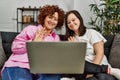 Mature mother and down syndrome daughter at home using computer laptop doing videocall Royalty Free Stock Photo