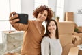 Mature mother and down syndrome daughter moving to a new home, standing by cardboard boxes taking a selfie picture Royalty Free Stock Photo