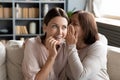 Mature mother telling rumors to curious surprised grownup daughter.