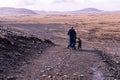 Mature mother walking her child on a path in a barren area surrounded by mountains