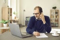 Mature multitasking man talking phone, looking at laptop making notes portrait Royalty Free Stock Photo