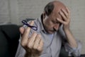 Mature old man on his 60s at home couch alone feeling sad and worried suffering alzheimer disease holding ribbon Royalty Free Stock Photo