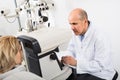 Mature optician examinating eyesight with aid of slit lamp Royalty Free Stock Photo