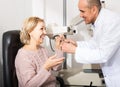 Mature optician examinating eyesight with aid of slit lamp Royalty Free Stock Photo