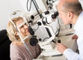 Mature optician examinating eyesight with aid of slit lamp Royalty Free Stock Photo