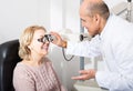 Mature optician examinating eyesight with aid of slit lamp Royalty Free Stock Photo