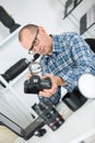 Mature photographer checking camera with magnifying glas Royalty Free Stock Photo