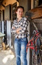 Mature positive female farmer standing near horse at stable Royalty Free Stock Photo