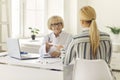 Mature positive woman doctor giving paper prescription to young woman patient Royalty Free Stock Photo