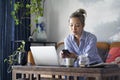 Mature asian woman working from home using laptop and cellphone Royalty Free Stock Photo