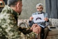 Mature psychologist holding picture with ink stain, Rorschach Inkblot in front of military man during therapy session Royalty Free Stock Photo