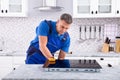 Mature Repairman Examining Induction Stove Royalty Free Stock Photo