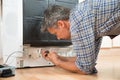 Repairman Repairing Dishwasher With Screwdriver Royalty Free Stock Photo