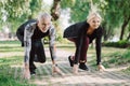 Mature runners standing in start positing on pavement in park