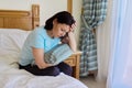 Mature sad suffering woman sitting on bed with pillow