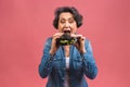 Mature senior woman eating burger with satisfaction. Grandmother enjoys tasty hamburger takeaway, delicious bite of burger, order