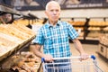Mature senor choosing bread and baking in grocery section of supermarket Royalty Free Stock Photo